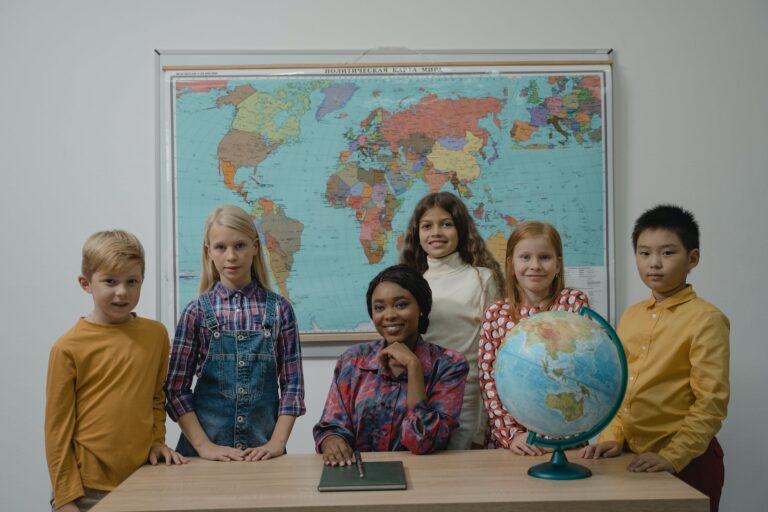 teacher and a group of children standing beside table with globe
