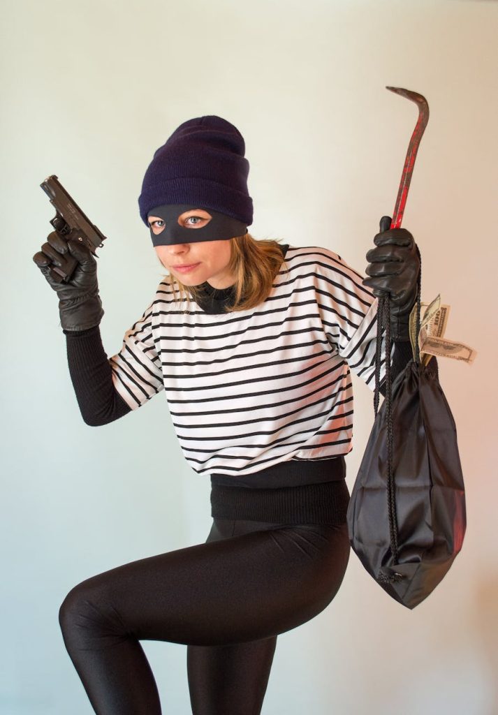 a woman in striped shirt wearing beanie while holding a gun