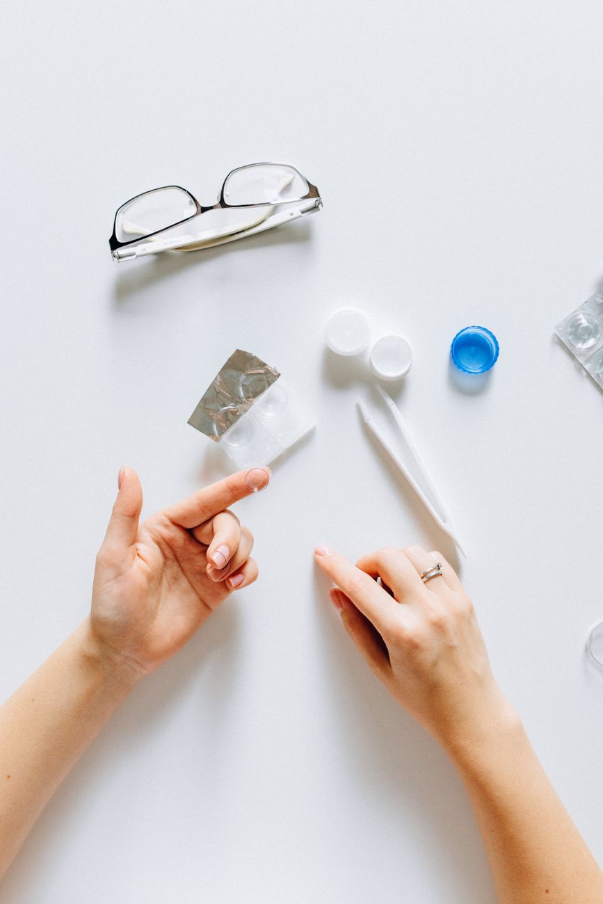 person putting contact lens on fingers
